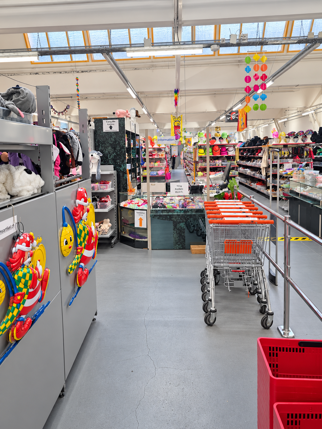 Eingangsbereich des Fasnachtsladens in Triengen mit Einkaufswagen, Infotheke und Regalen voller Hüte