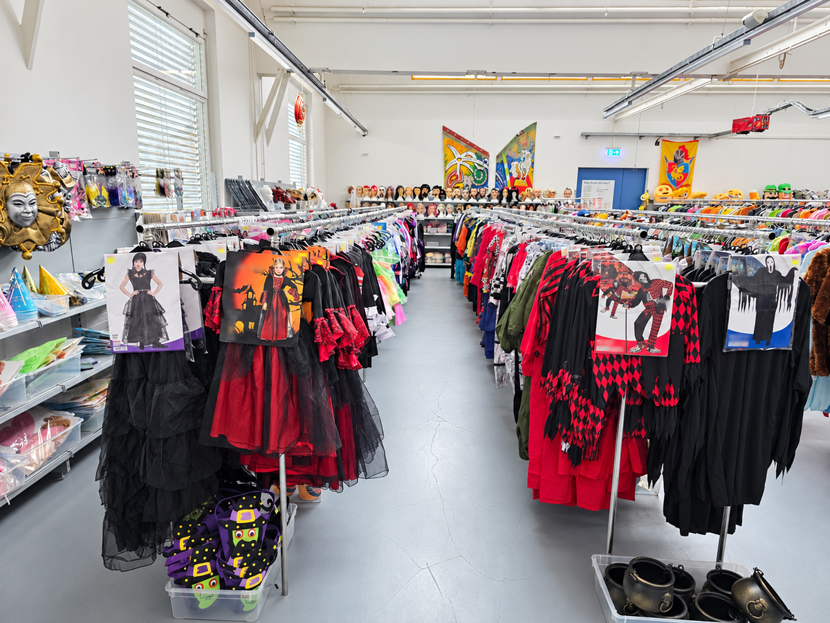 Halloween-Kostüme für Kinder und Erwachsene, im Hintergrund eine Wand mit Perücken